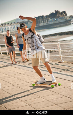 Un jeune homme la planche à roulettes sur la promenade à Aberystwyth, Pays de Galles, Royaume-Uni 26 mars 2012 : Les gens apprécient la températures plus chaudes au bord de la mer. L'ensemble du Royaume-Uni est en pèlerin plus des températures typiques de la fin de juin. Banque D'Images