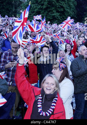 Londres, Royaume-Uni. Le 4 juin 2012. Fans de tous les âges en brandissant des drapeaux qu'ils regarder et apprécier le Concert pour célébrer le Jubilé de diamant de la reine sur les grands écrans à St James's Park. Banque D'Images