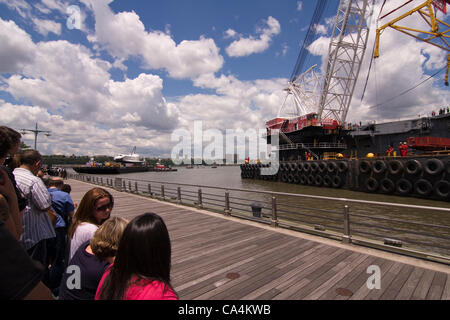 Le 6 juin 2012. New York City USA. Une foule de spectateurs attend l'arrivée de la navette spatiale Enterprise sur la gauche, qui se trouve au sommet d'une barge dans l'Hudson. La navette sera transférée à l'USS Intrepid porte-avion par une grue de levage lourd marin sur la droite. Banque D'Images