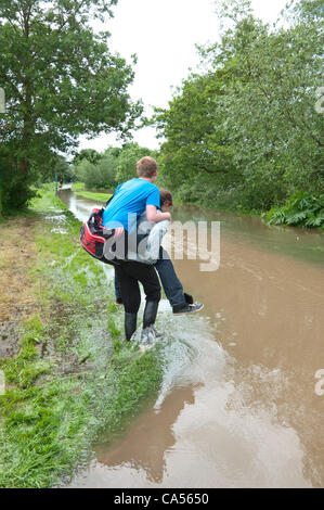 Hereford, Royaume-Uni. 9 juin 2012. Une jeune femme donne à un ami un "piggy back' ride dans les eaux d'inondation le long du chemin de halage. La rivière Wye éclate son unseasonal banques après de fortes pluies. Banque D'Images