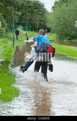 Hereford, Royaume-Uni. 9 juin 2012. Une jeune femme donne à un ami un "piggy back' ride dans les eaux d'inondation le long du chemin de halage. La rivière Wye éclate son unseasonal banques après de fortes pluies. Banque D'Images