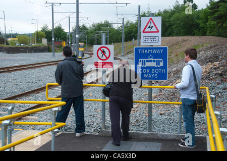 13 juin 2012. Les amateurs de tram à l'arrêt de tramway d'oreillons Oldham attendent le tram pour traverser à l'autre piste Après avoir terminé le premier transport de passagers sur la nouvelle ligne de tramway Metrolink à Oldham. Banque D'Images