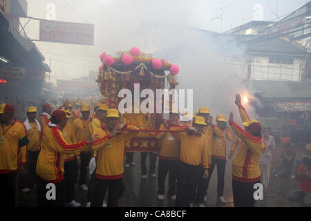 La province de Samut Sakhon, Thaïlande, 26 juin 2012 . Les hommes porte pilier Ville Dieu par le marché . L'Chaopho Lak Mueang Procession ou le culte de l'City-God Parade a lieu en juin chaque année, à la berge en face de l'hôtel de ville. L 'Chaopho Lak Mueang' est ensuite placé dans un palanquin sur un bateau de pêche, qui est magnifiquement décorée de drapeaux, et flottait le long de la Tha Chin de Talat Maha Chai à Tha Chalom dans le domaine de la Wat Suwannaram et à la suite d'Wat Chong Lom, donnant la possibilité à la population de rendre hommage et d'avoir la bonne fortune. Banque D'Images