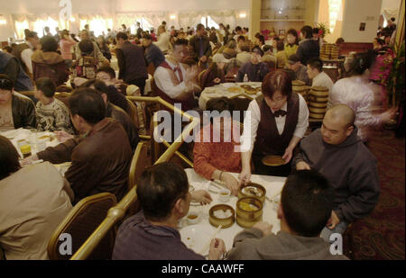 Une serveuse s'arrête à une table pour servir un plat de dim sum dans toute la salle à manger principale du restaurant légendaire palace à Oakland, Californie le Dimanche, Janvier 25, 2004. (Sherry LaVars/fois) Banque D'Images