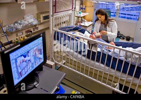 27 févr. 2008 - Los Angeles, Californie, USA - dans un hôpital de Californie, une mère prend soin de son bébé souffrant de moelle bifida. Prendre note des résultats de surveillance de l'électroencéphalographie (EEG) de l'électrode "PAC" et d'épais massifs de câbles à l'ordinateur (au premier plan) la surveillance de l'état de l'enfant. Spina b Banque D'Images