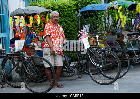 Un pilote de cylo ou de pousse-pousse à vélo prend un frein lors de la célébration du nouvel an thaïlandais sur la route de Sukhumvit, Bangkok, Thaïlande, le vendredi 13 avril 2012. Bangkok célèbre le nouvel an thaïlandais avec le festival traditionnel de l'eau Songkran. Les cyclos sont une forme d'énergie renouvelable. Credit: Kraig Lieb Banque D'Images