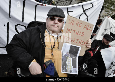 18/04/12, London, UK : une mobilité protestataire est titulaire d'un placard et fait partie d'un groupe d'utilisateurs en fauteuil roulant qui bloquer les routes autour de Trafalgar Squrae. La protestation a été de mettre en lumière les problèmes que rencontrent les personnes handicapées, en particulier pour modifier les prestations d'invalidité. Banque D'Images