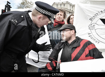 18/04/12, London, UK : un policier parle à un utilisateur en fauteuil roulant qui fait partie d'un groupe bloqué les routes à Trafalgar Square pour protester contre les modifications apportées aux prestations d'invalidité. Banque D'Images