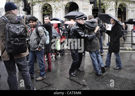 18/04/12, London, UK : un agent de police arrête un manifestant alors qu'il tente de s'exécuter à partir de la chaussée dans une tentative de parvenir à un petit groupe de personnes handicapées bloquant la route. L'action a été pour protester contre les modifications apportées à des prestations d'invalidité. Banque D'Images