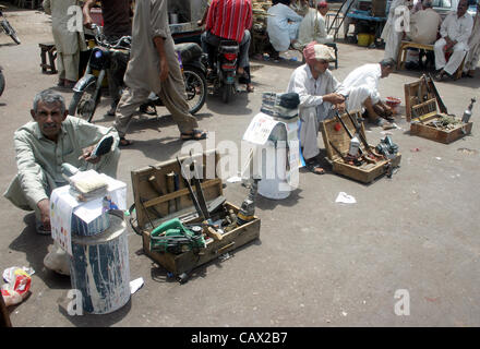 Travail sans emploi s'asseoir à une attente de la route pour leur emploi, à la veille de la fête du Travail à Karachi le lundi 30 avril 2012. Banque D'Images