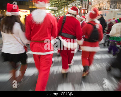 Plusieurs Santas à pied et bras bras vers le bas de la rue au cours de chaque année, Santa Con pub crawl avec des milliers habillé en père Noël, à New York, New York, United States Banque D'Images