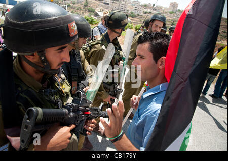 AL MASARA, TERRITOIRES PALESTINIENS OCCUPÉS - 18 MAI 2012 : un activiste non-violente palestinienne affronte les soldats israéliens lourdement armés dans une manifestation hebdomadaire contre le mur de séparation en Cisjordanie, Al-Masara. Banque D'Images