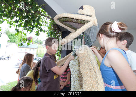 Les enfants travaillent ensemble pour décorer des sculptures de fil avec narcisse et de les rendre prêts pour le défilé du 53e Festival de narcisses, Bad Aussee, Ausseerland, Styrie, Autriche, le samedi 19 mai 2012. Banque D'Images