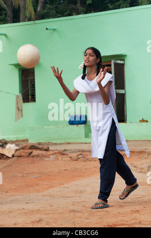 Jeune fille de l'école indienne de lancer un ballon dans un village de l'Inde rurale. L'Andhra Pradesh, Inde Banque D'Images