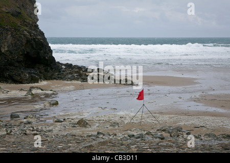 Plage de Porth Chapelle, rouge d'un drapeau. Banque D'Images