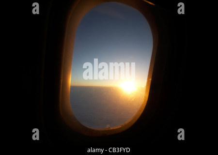 Lever du soleil à travers la fenêtre des aéronefs de passagers pendant le vol. Banque D'Images