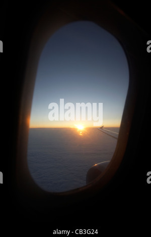 Lever du soleil à travers la fenêtre des aéronefs de passagers pendant le vol. Banque D'Images