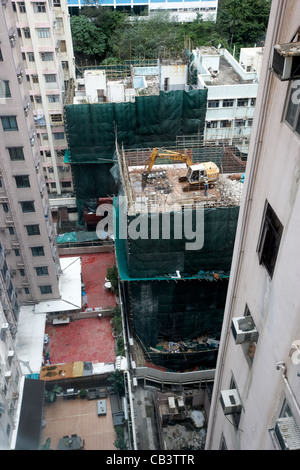 Pelle au-dessus du bâtiment les travaux de construction en cours entre des tours d'appartements de logement à proximité de l'île de hong kong Banque D'Images