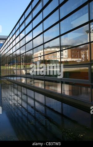 La façade de verre reflétant la construction d'autres bâtiments reflètent également dans l'eau - Banque D'Images