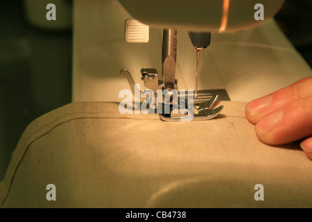 Libre de machine à coudre couture toile beige tenue par les doigts de l'homme Banque D'Images