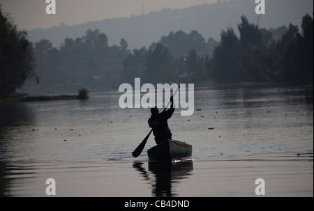 Un homme utilise un bateau à travers le canal de Xochimilco, au sud de Mexico City Banque D'Images