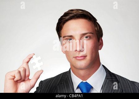 Un business man holding jigsaw piece dans sa main Banque D'Images