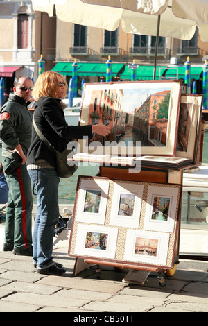 Un artiste vénitien affiche ses peintures de la ville au pied du Pont du Rialto à Venise, Italie. Banque D'Images