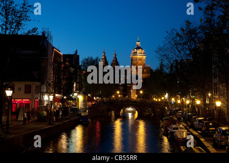 Vue de nuit sur un canal dans le Quartier Rouge avec Sint-Nicolaaskerk en arrière-plan. Amsterdam, Pays-Bas. Banque D'Images