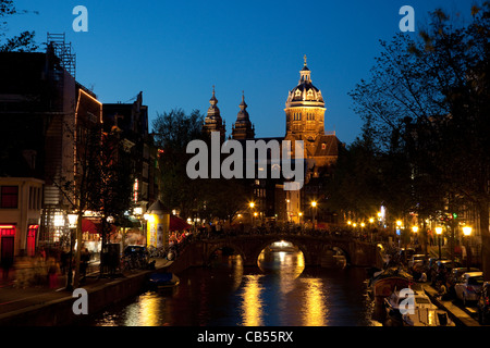 Vue de nuit sur un canal dans le Quartier Rouge avec Sint-Nicolaaskerk en arrière-plan. Amsterdam, Pays-Bas. Banque D'Images