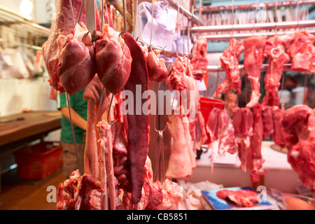 Viandes et abats frais accroché dans une cabine de bouchers dans un marché en plein air dans le quartier de Mong Kok, Kowloon Hong Kong région administrative spéciale de Chine Banque D'Images