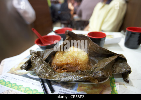 Boulette de riz colle avec du porc enveloppé dans une feuille de lotus dim sum tim ho wan dans un restaurant étoilé Michelin district Mong Kok Banque D'Images