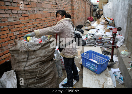 Jeune femme chinoise en marche petit retour au dépôt de la rue où les migrants peser et vendent ce qu'ils ont recueillis, Beijing, Chine Banque D'Images