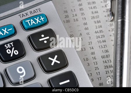 Détail de calculatrice, se concentrant la touche TAX, à côté d'une feuille de papier avec des chiffres et un stylo en métal. Banque D'Images