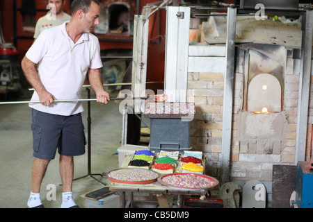 Un artisan dans une usine de Murano travaille sur la production d'un morceau de verre décoratif Banque D'Images