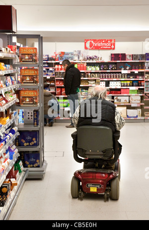 Un homme handicapé magasiner sur son scooter des personnes handicapées dans un supermarché de Waitrose, Royaume-Uni; magasin d'accès handicapés au Royaume-Uni. Banque D'Images