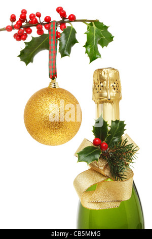 Sur le thème de Noël, champagne bouteille décorée avec Holly et ruban à côté d'une boule d'or suspendu à une branche de houx Banque D'Images