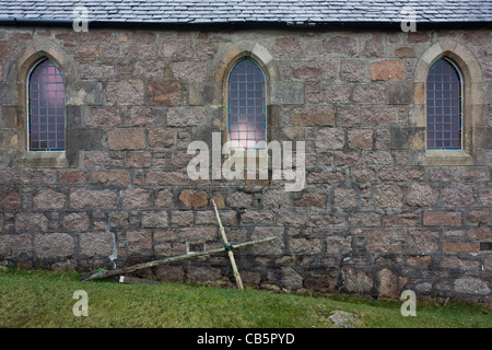 Croix Crucifix prop appuyé contre mur extérieur de l'église St Ernan, Fionnphort, Ile de Mull, en Ecosse. Banque D'Images