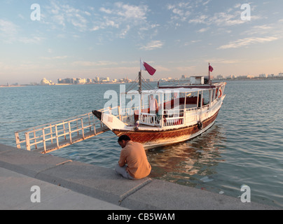 Un dhow utilisé pour des excursions autour de la baie de Doha, Qatar, attend les passagers sur la Corniche, au coucher du soleil Banque D'Images