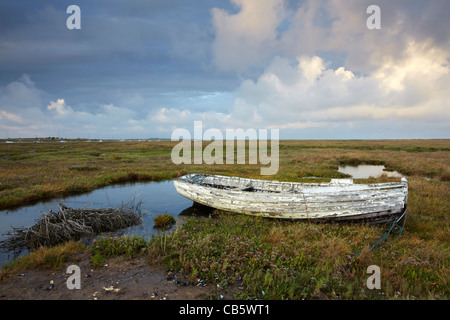 Un bateau abandonné parmi les Saltmarsh à Brancaster Staithe sur la côte nord du comté de Norfolk un soir d'été Banque D'Images