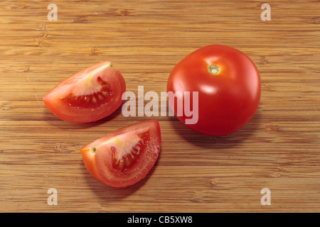 Deux quarts de tomate et de tomate sur une planche à découper Banque D'Images