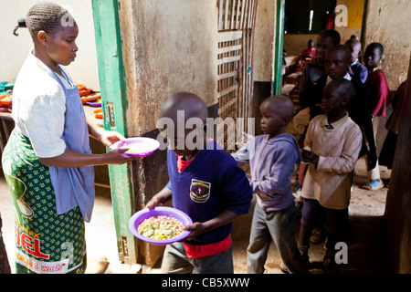 Les enfants de l'école recevoir la nourriture fraîchement cuit à Kibera, Nairobi école où une ONG exécute un programme d'alimentation à l'heure du déjeuner. Banque D'Images