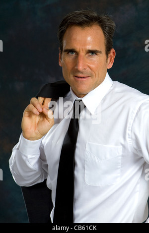 Confident businessman portant chemise blanche et cravate a son manteau drapé sur l'épaule. Banque D'Images