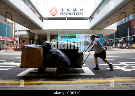 Homme pousse la livraison panier passé Hang Seng Bank ac central district, l'île de hong kong, Hong Kong, Chine flou délibéré Banque D'Images