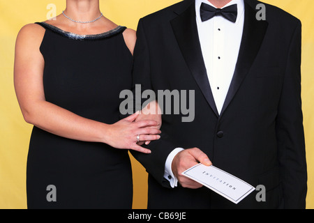 Photo d'un couple en tenue de soirée tenue de soirée, l'homme est maintenant une invitation. Banque D'Images