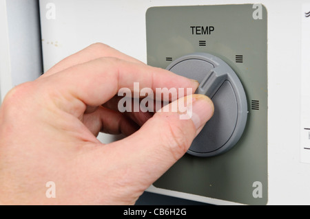 L'homme règle le thermostat sur une chaudière domestique Banque D'Images