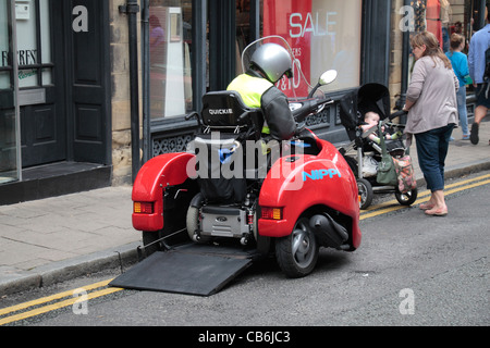 Un homme en fauteuil roulant de la saisie d'un scooter à trois roues Nippi à Chester, Cheshire, Royaume-Uni. Banque D'Images
