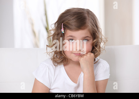 Jeune fille assise sur un canapé Banque D'Images
