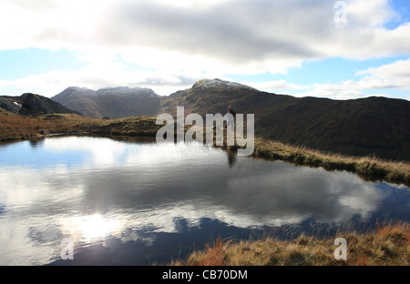 Hillwalker en tenant de l'avis de An Caisteal (995m) et a'Chroin Beinn (938m) d'une Lochan sur les pentes de Cruach Ardrain Banque D'Images