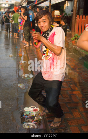 Les jeunes lao de Hamming avec un pistolet à eau au cours d'une lutte à l'eau pour fêter le Nouvel An Lao (Pi Mai Lao), Luang Prabang, Laos Banque D'Images