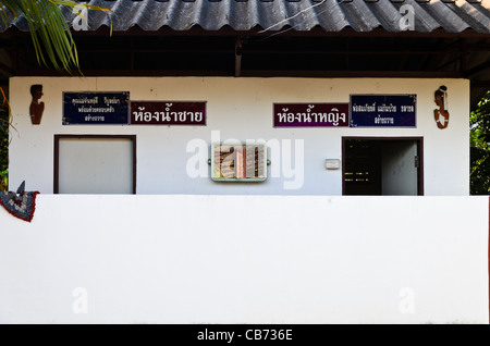 Construction de toilettes avec des murs blancs et des chiffres de l'homme par la porte gauche et la femme par la porte de droite avec l'écriture thaï dans le nord de la Thaïlande Banque D'Images